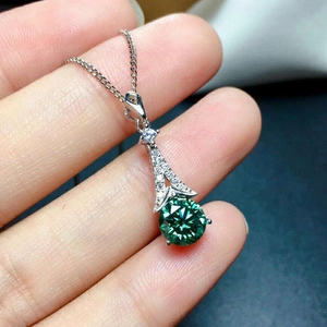Elegant silver necklace with a brilliant round green moissanite pendant held in hand
