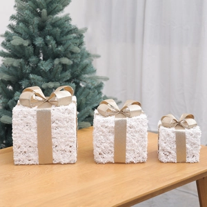 Three-piece white Christmas gift box set with champagne gold ribbons on wooden desk