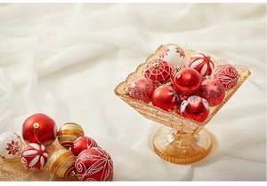 Assorted red and gold Christmas ornaments with snowflake patterns in a glass display