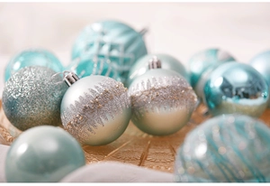 Macro shot of mint green and silver Christmas ornaments with diverse textures in a tray