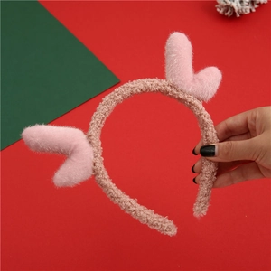 Pink plush reindeer antler headband with soft lamb wool texture on vibrant red background