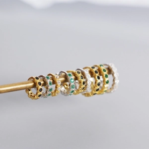 Macro shot of S925 sterling silver huggie earrings with colorful zircon stones on metal stand