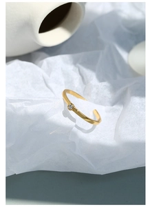 Dettaglio dell'anello aperto placcato oro minimalista con un piccolo zircone luminoso