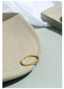 Dettaglio di anello regolabile placcato oro con piccolo diamante su superficie in tessuto