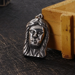 Macro shot of stainless steel Jesus head pendant with detailed relief carving on wood