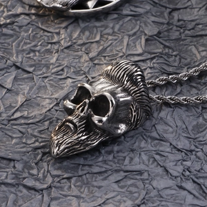 Close-up of silver skull pendant with mustache and pompadour on a twisted rope chain