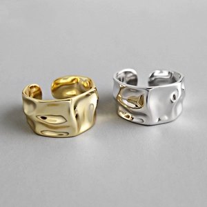 Detailed view of gold and silver irregular textured wide rings with a wrinkled metal finish