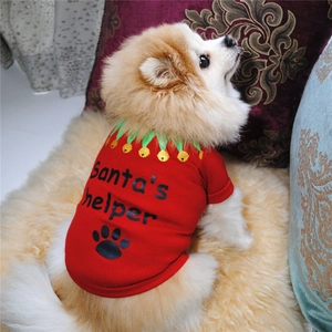 Detail of red cotton Christmas dog T-shirt with Santa's helper text on plush carpet