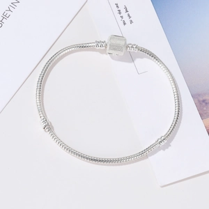 Minimalist silver snake chain bracelet with textured cylindrical clasp on high-end background
