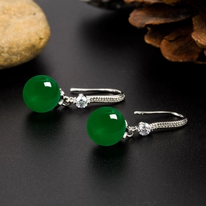 Ethnic green chalcedony earrings with diamonds and silver hooks on a natural pebble background