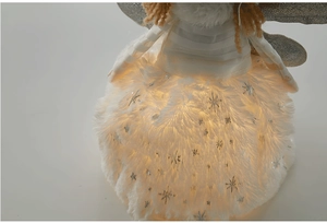 Detailed view of plush angel ornament with glowing warm LED lights and silver sequins