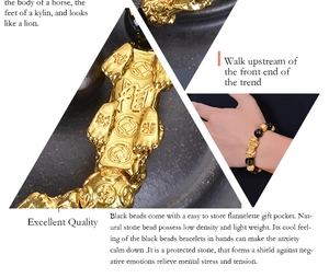 Macro detail of obsidian PiXiu bracelet showing gold charms and beads on person