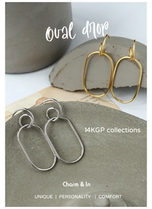 Close-up of oval drop earrings in 14K gold plated and silver finish on a grey stand