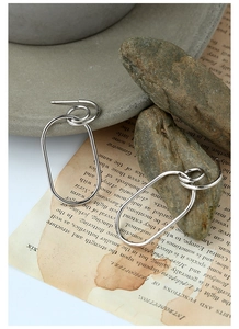 Detail of silver geometric interlocking oval hoop earrings on vintage book page