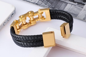 Detail of gold-plated bicycle chain links with black braided leather on white decor