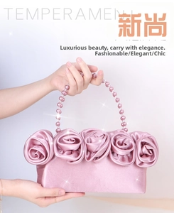 Dettaglio borsa da sera in raso rosa con rose in tessuto e manico di perle