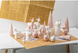 Close-up of pink and pearlescent white ceramic elk figurines on vintage newspaper