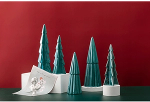 Close-up of assorted green ceramic Christmas trees on dark red background decor
