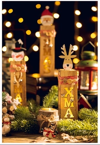 Close-up of three lighted wooden Xmas figurines with Santa, snowman and elk in warm light