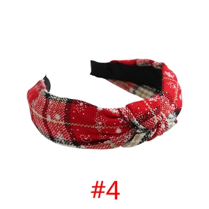 Detail of red plaid Christmas headband featuring white snowflakes and a top knot design