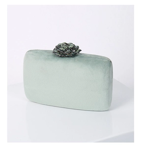 Close-up of mint green velvet evening clutch with petal-shaped rhinestone clasp