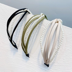 Detail of layered headband with intertwined faux pearls and textured fabric on wall