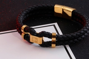 Macro shot of double-layer black braided leather bracelet with gold stainless steel cross