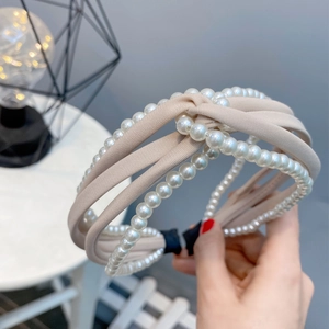 Detail showing multi-layer knotted headband with white pearls and beige chiffon fabric wrap