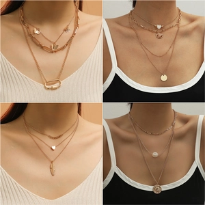 Detail view of four multi-layered gold metal necklaces with butterfly and heart charms