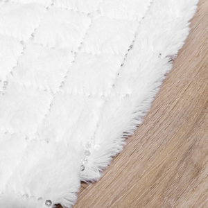 White faux fur Christmas tree skirt with silver sequins and diamond pattern on wood floor