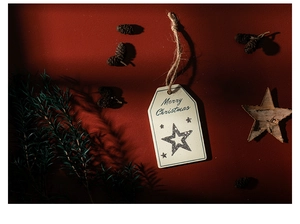 Close-up of beige Christmas tag with black star and Merry Christmas text on red background