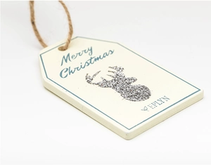 Close-up of wooden Christmas tag with silver glitter reindeer and Merry Christmas text