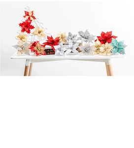 Close-up of artificial Poinsettia flowers with glitter finish on white wooden desk