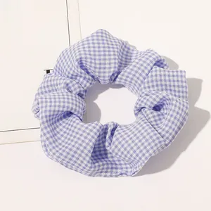 Detailed view of blue and white checkered fabric scrunchie with elastic pleated texture