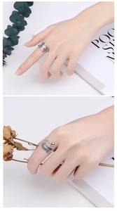 Detail of adjustable silver feather and arrow ring on a hand with minimalist background
