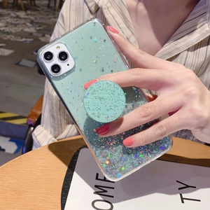 Detail of mint green starry glitter phone case with matching pop socket on a wooden table