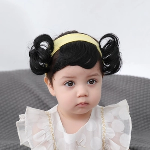 Detail of baby headband with black double bun wig and soft yellow fabric bow accessory
