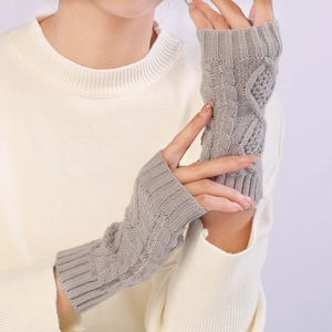 Close-up of light grey knit fingerless gloves with a classic diamond cable pattern