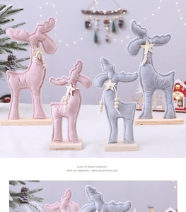 Détail de rennes de Noël en peluche rose et grise avec socle en bois et étoile