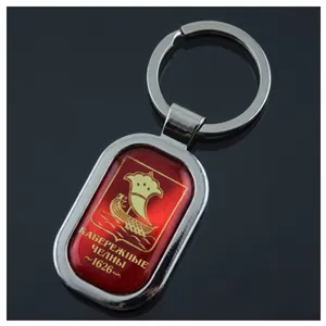 Detail of silver alloy keychain with oval red resin crest featuring a golden ship