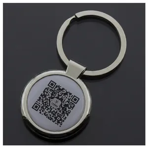 Detailed view of a round silver metal keychain with a white QR code insert center