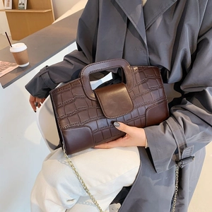 Retro dark brown crocodile pattern handbag with gold chain strap in a cafe setting