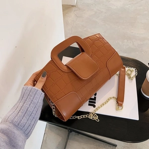 Detail of caramel brown crocodile embossed leather handbag with gold chain strap
