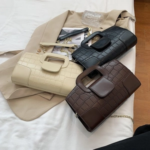 Three crocodile pattern handbags in beige, black, and brown with gold chain straps