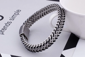Macro shot of men's double-row steel chain bracelet with woven cord and magnetic clasp
