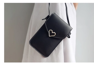 Détail du sac de téléphone noir avec fermoir cœur doré et coutures blanches contrastées
