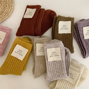 Flat lay of colorful ribbed wool blend socks with branded labels on white tabletop