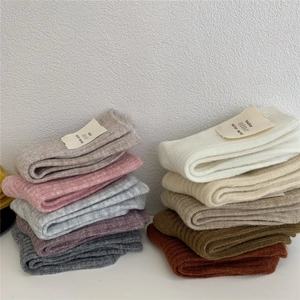 Close-up of thick wool socks in multiple colors stacked neatly on a white background