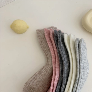 Flat lay of colorful thick wool socks in beige, pink, and grey with a knit texture