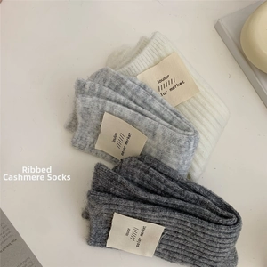 Detail of ribbed wool cashmere socks in white and grey colors with brand label